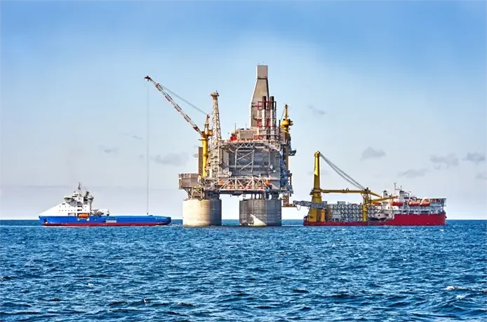 Oil rig and support vessel on offshore area. Blue sky background